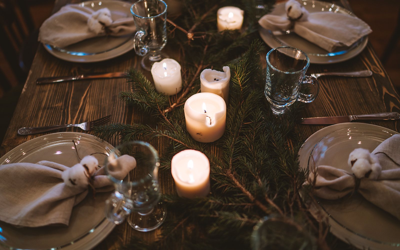 Mesa de Nochebuena decorada con velas encendidas y ramas de pino, preparada para la cena de Navidad
